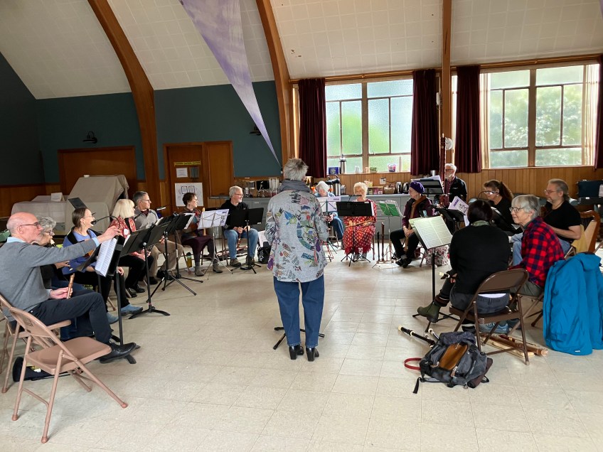 Asemi-circle of musicians face a leader